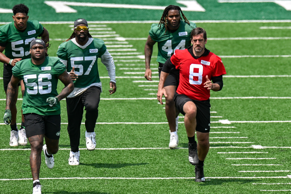 Jets players, including QB Aaron Rodgers (8), warm up at OTAs
